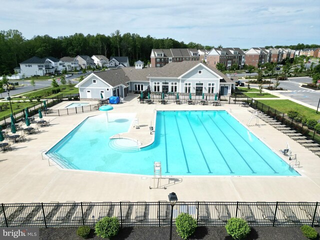 community pool with fence, a patio area, and a residential view