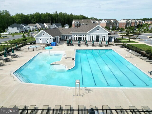 community pool with a residential view, fence, and a patio
