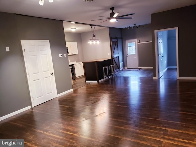 unfurnished living room featuring a ceiling fan, baseboards, visible vents, and dark wood-type flooring