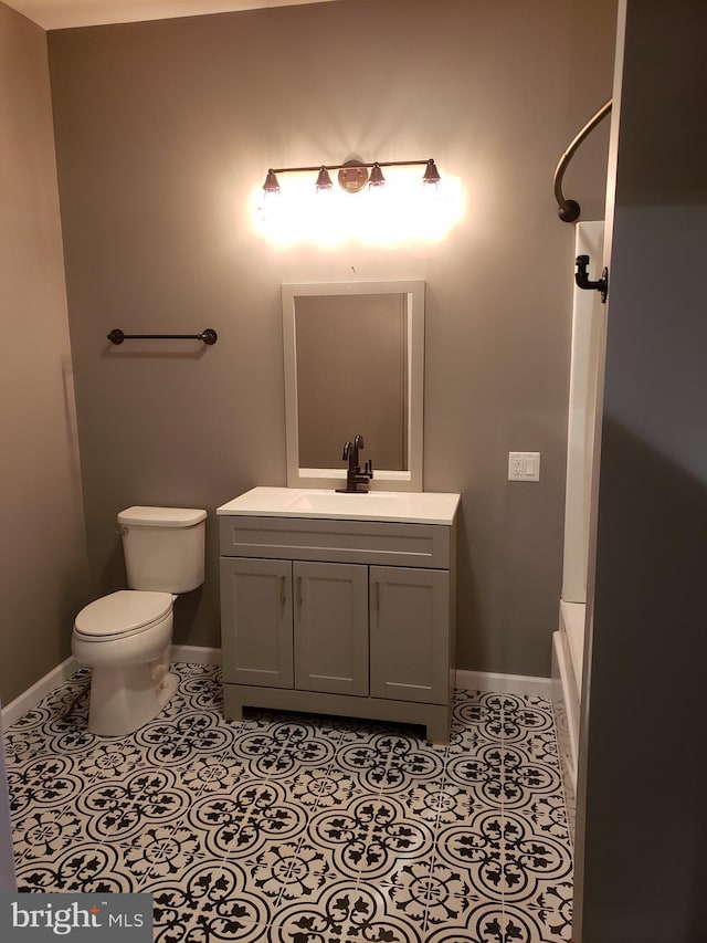 bathroom with baseboards, tile patterned flooring, toilet, and vanity