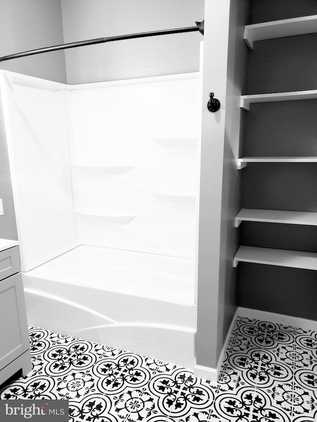bathroom featuring tile patterned floors, baseboards, vanity, and  shower combination