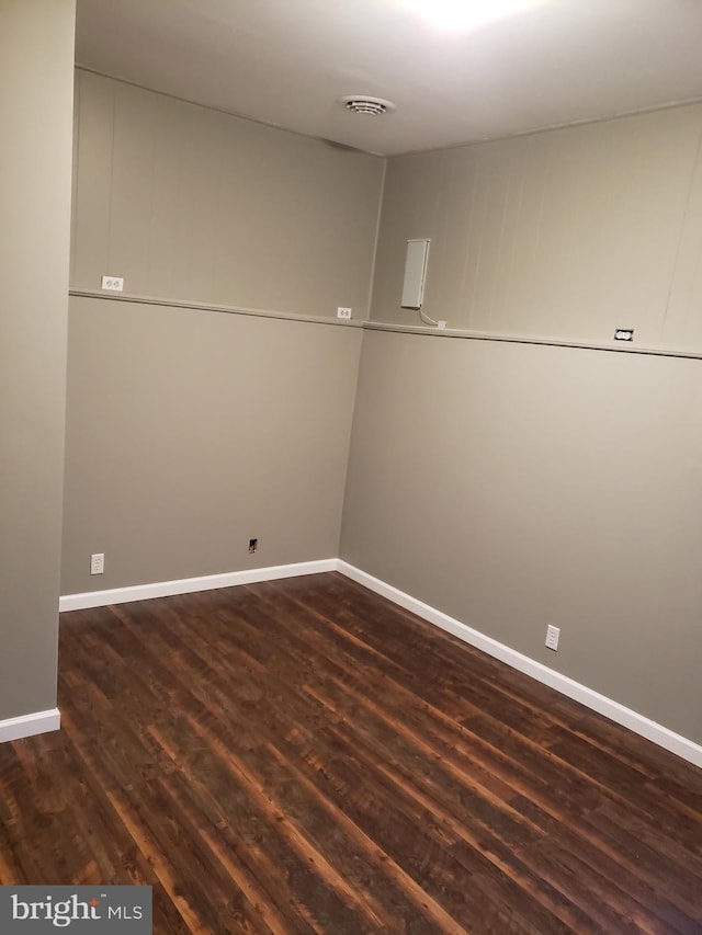 spare room with baseboards, dark wood-style floors, and visible vents