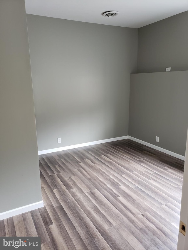 unfurnished room featuring baseboards, wood finished floors, and visible vents