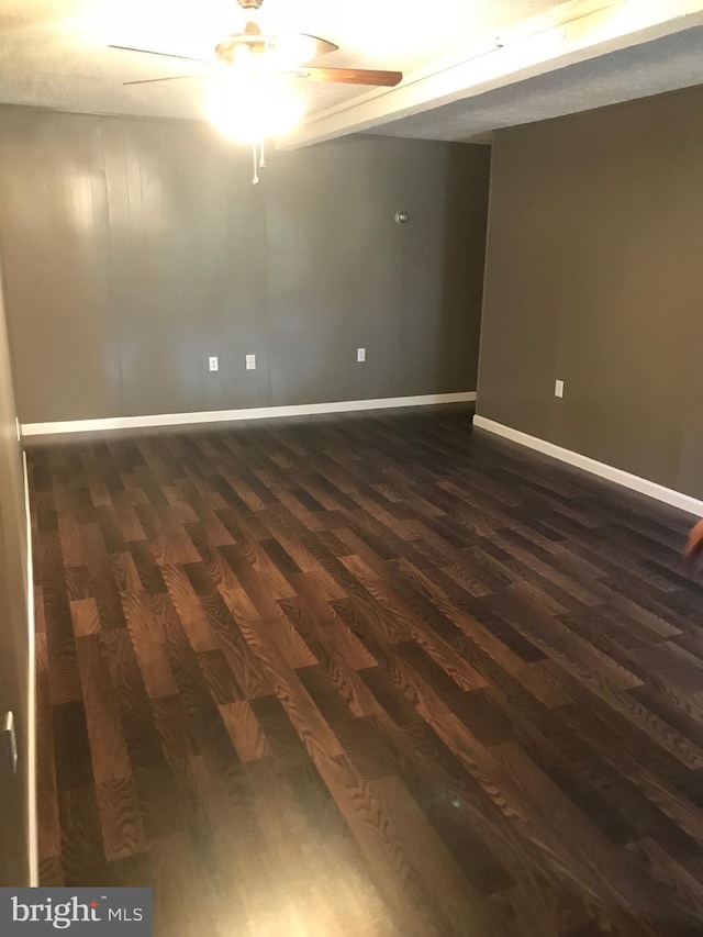 empty room with baseboards, ceiling fan, and dark wood-style floors