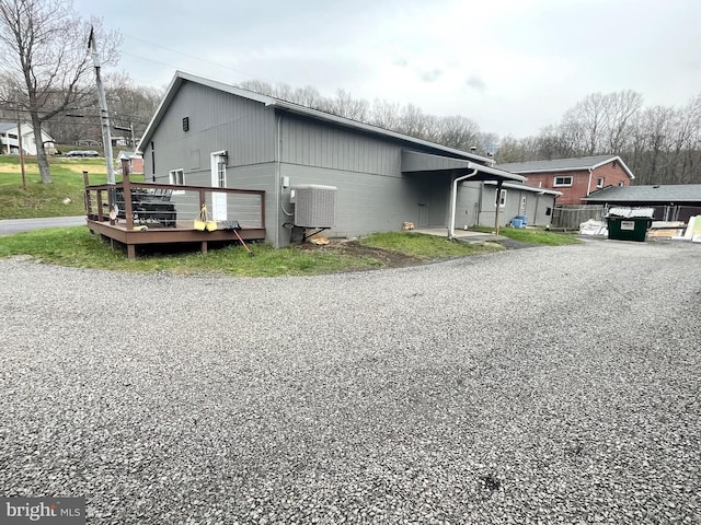 view of side of property featuring a deck, central AC unit, and concrete block siding
