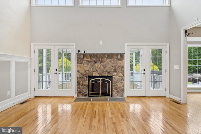 301 Gentle Breeze Cir, Fredericksburg, VA 22406 - unfurnished living room featuring french doors, a towering ceiling, wood finished floors, and a stone fireplace
