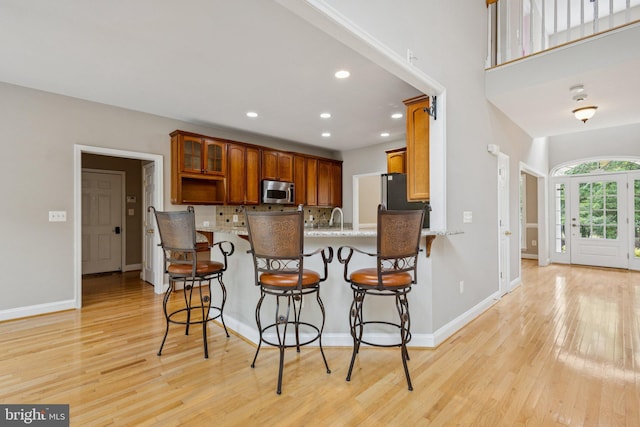 301 Gentle Breeze Cir, Fredericksburg, VA 22406 - kitchen featuring appliances with stainless steel finishes, light wood-style floors, a peninsula, recessed lighting, and light stone countertops