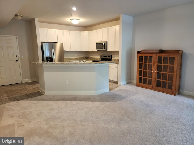 kitchen featuring appliances with stainless steel finishes, light carpet, light stone countertops, white cabinetry, and baseboards