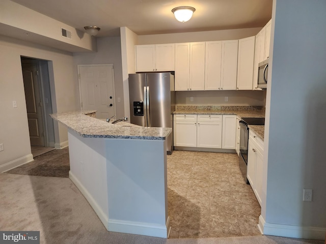 kitchen with stainless steel appliances, white cabinetry, a kitchen island with sink, light stone counters, and baseboards