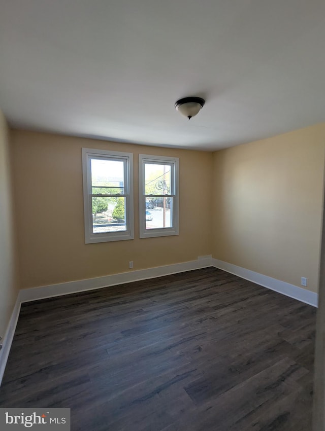 empty room featuring baseboards and dark wood-style flooring