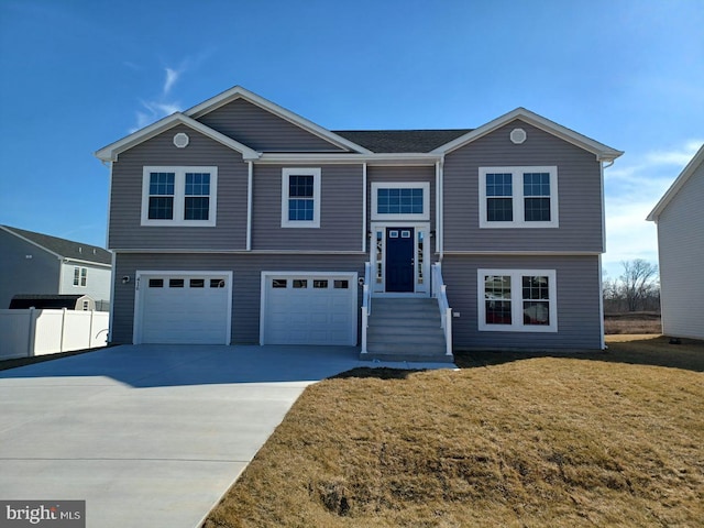 bi-level home featuring a garage, a front lawn, fence, and concrete driveway
