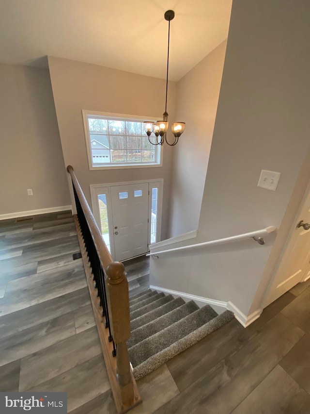 stairs featuring baseboards, a chandelier, and wood finished floors