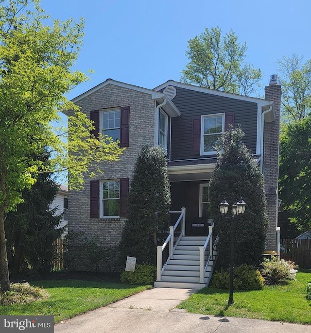7707 W Dr, Glen Burnie, MD 21060 - traditional-style house featuring a porch, a chimney, brick siding, and a front yard