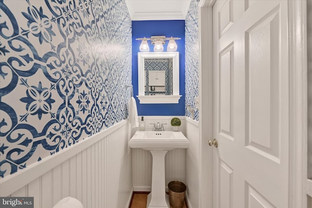 7707 W Dr, Glen Burnie, MD 21060 - bathroom featuring a wainscoted wall, wallpapered walls, a sink, ornamental molding, and a decorative wall