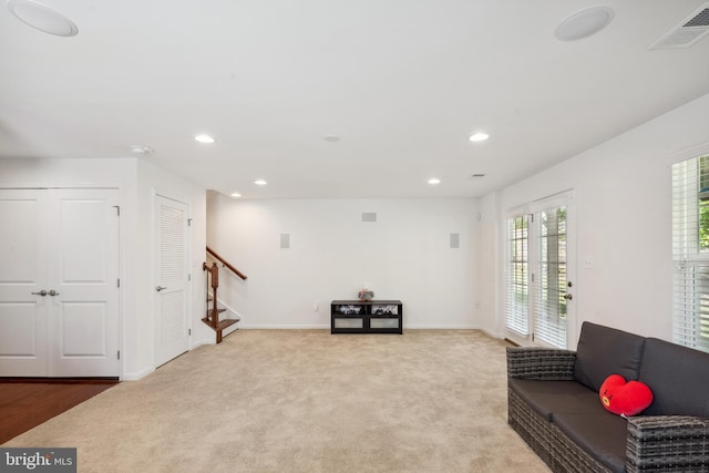 living area with recessed lighting, light colored carpet, visible vents, and stairway