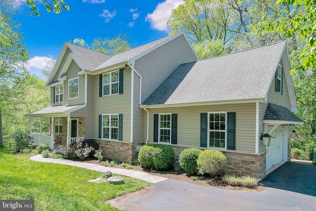 view of front of home featuring a shingled roof, a front lawn, and stone siding