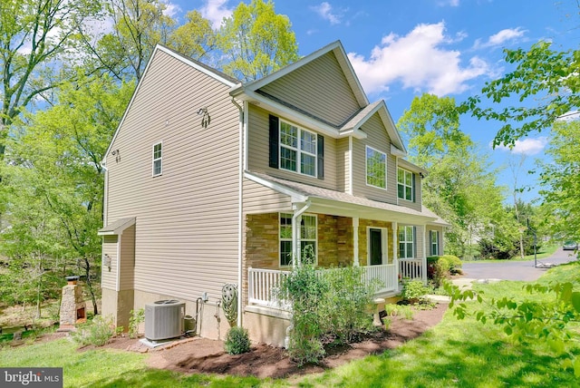 view of property exterior with covered porch, cooling unit, and stone siding