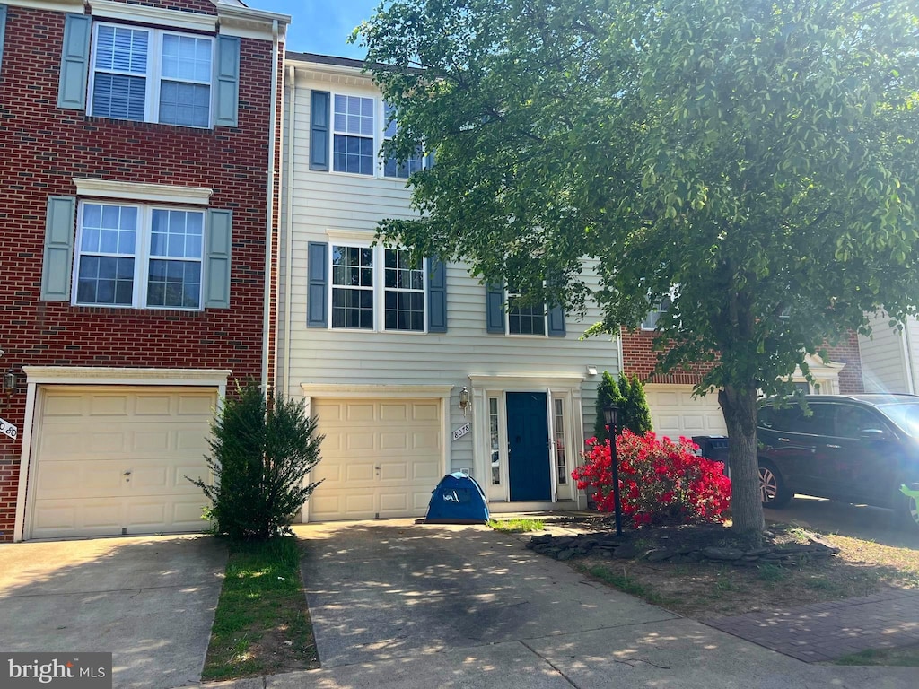 multi unit property with brick siding, a garage, and driveway