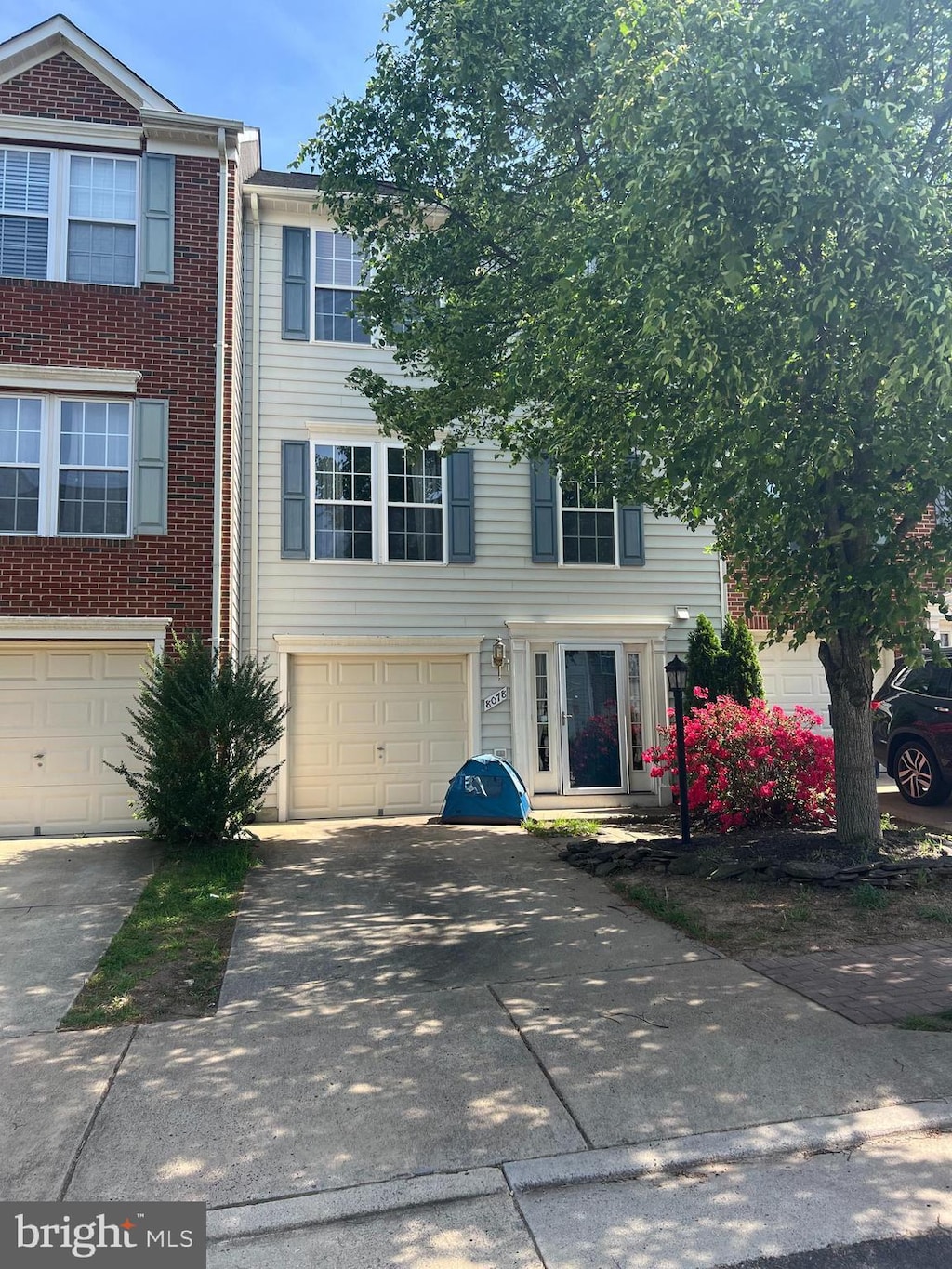 view of property with an attached garage, driveway, and brick siding