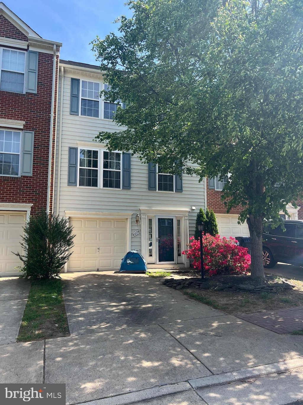multi unit property featuring an attached garage, driveway, and brick siding