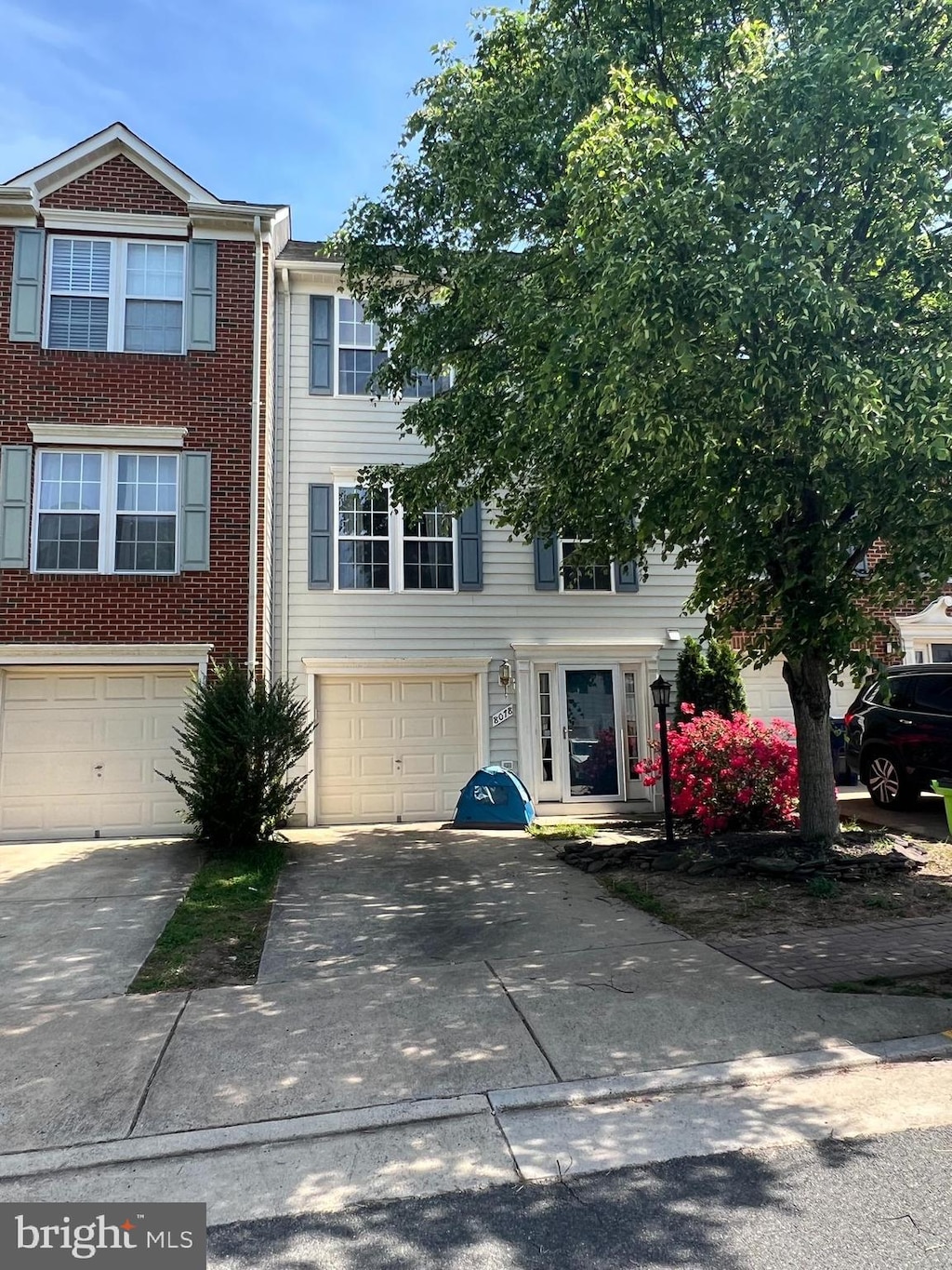 townhome / multi-family property with a garage, driveway, and brick siding