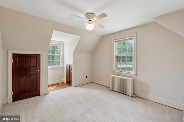 additional living space featuring radiator heating unit, carpet flooring, lofted ceiling, and a wealth of natural light