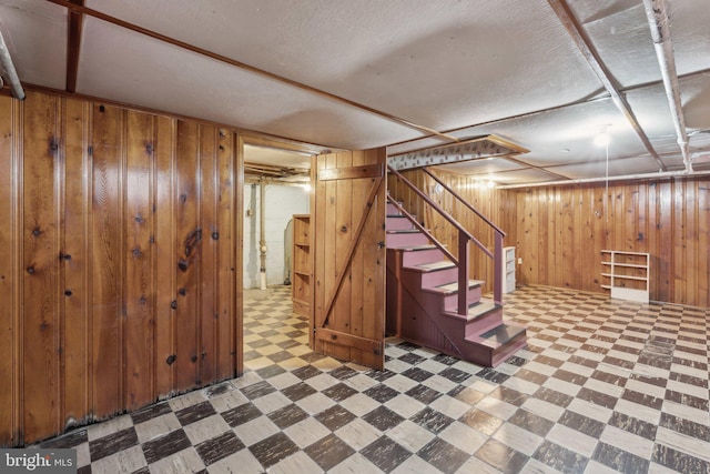finished below grade area featuring wood walls, stairs, and tile patterned floors