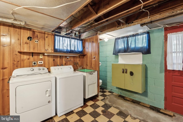 washroom with laundry area, concrete block wall, tile patterned floors, wood walls, and washing machine and dryer