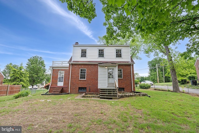 back of property featuring fence, a chimney, a lawn, and brick siding