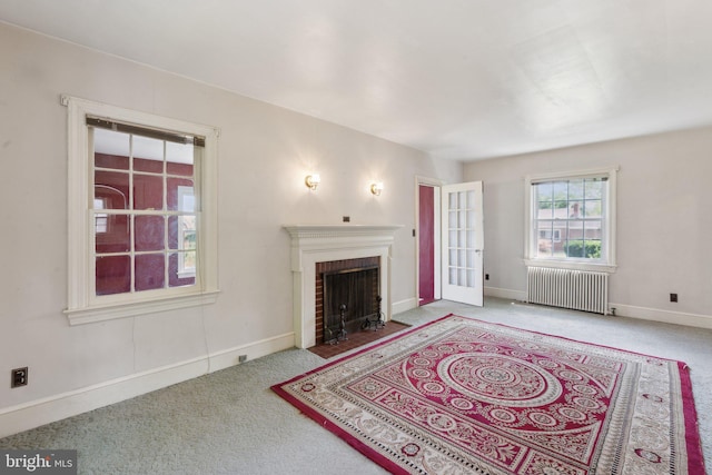 unfurnished living room with radiator, baseboards, a fireplace, and carpet floors