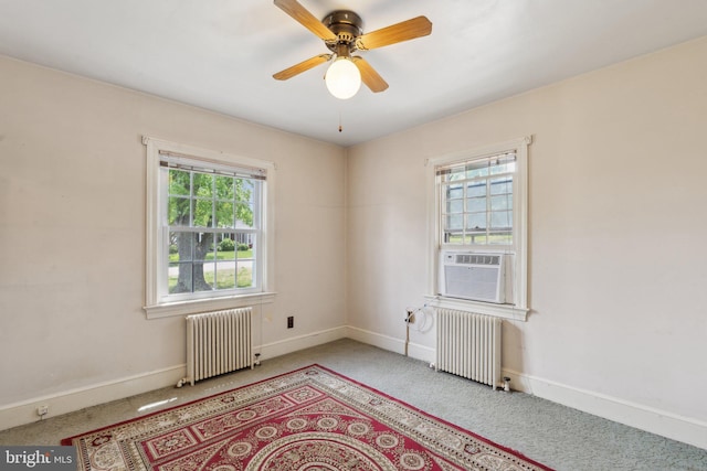 carpeted spare room featuring baseboards, a ceiling fan, radiator heating unit, and cooling unit
