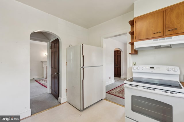 kitchen with white appliances, arched walkways, brown cabinetry, baseboards, and under cabinet range hood