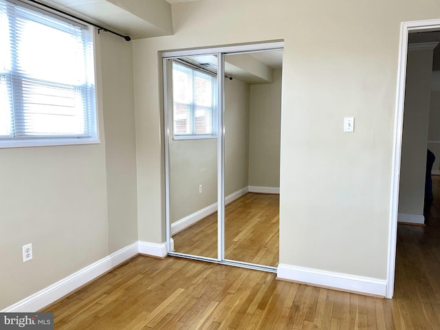 unfurnished bedroom with baseboards, light wood finished floors, and a closet