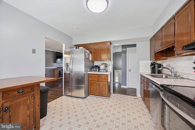 kitchen with a sink, appliances with stainless steel finishes, decorative backsplash, and light countertops