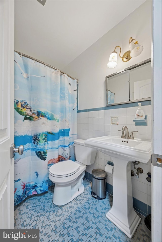 bathroom featuring wainscoting, curtained shower, toilet, and tile walls