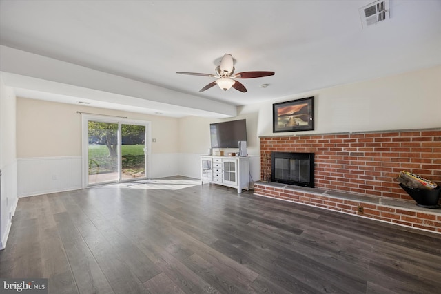 unfurnished living room featuring visible vents, wainscoting, wood finished floors, and a fireplace