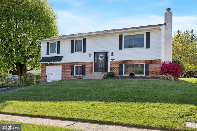 bi-level home with brick siding, an attached garage, a chimney, and a front lawn