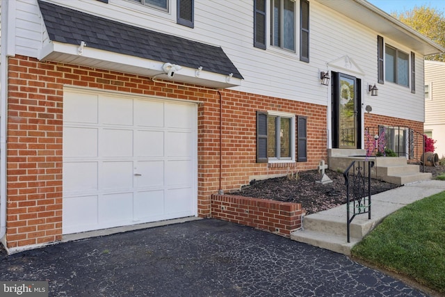 view of front facade with brick siding, driveway, roof with shingles, and a garage