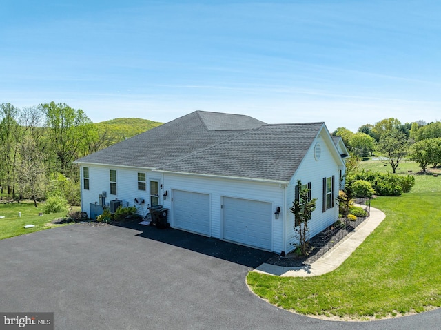 view of front of home featuring roof with shingles, an attached garage, a front lawn, and aphalt driveway