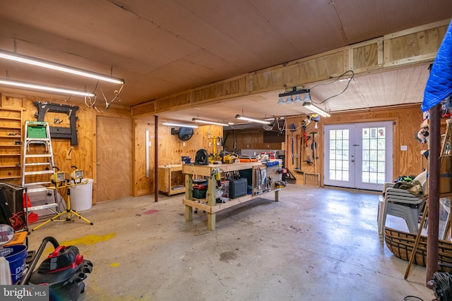 garage featuring french doors, wood walls, and a workshop area