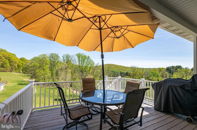 wooden terrace featuring a lawn, a forest view, grilling area, and outdoor dining area