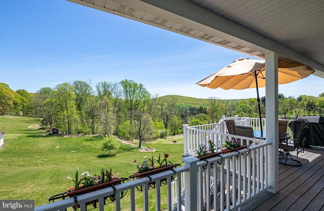 wooden deck with a yard, a forest view, and outdoor dining area