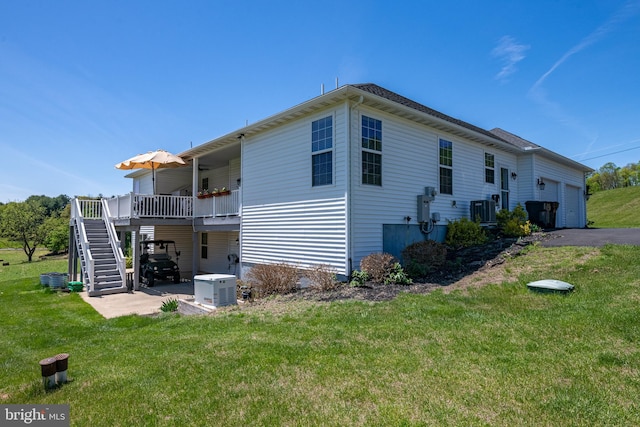 back of property with central air condition unit, a wooden deck, a lawn, and stairway