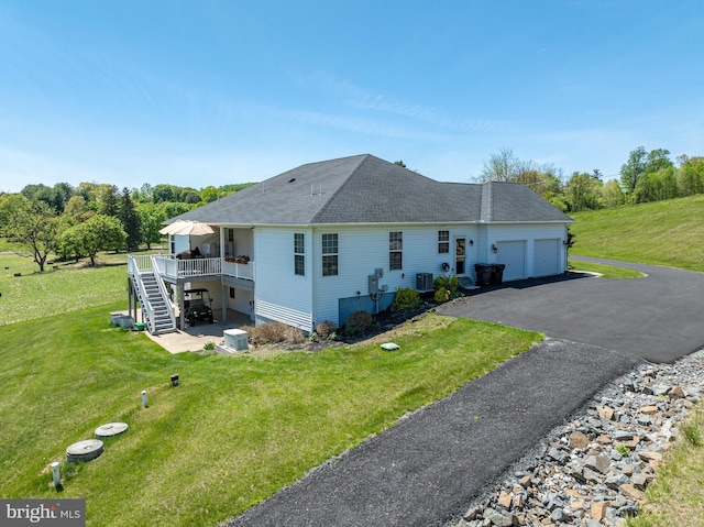view of side of home featuring a shingled roof, aphalt driveway, a garage, a deck, and stairway