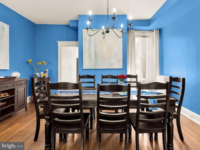 dining area with baseboards, wood finished floors, and a notable chandelier