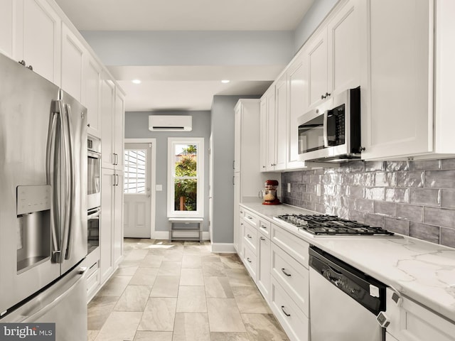 kitchen featuring white cabinets, an AC wall unit, stainless steel appliances, baseboards, and recessed lighting