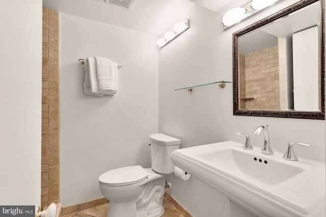 bathroom with toilet, baseboards, a sink, and tile patterned flooring