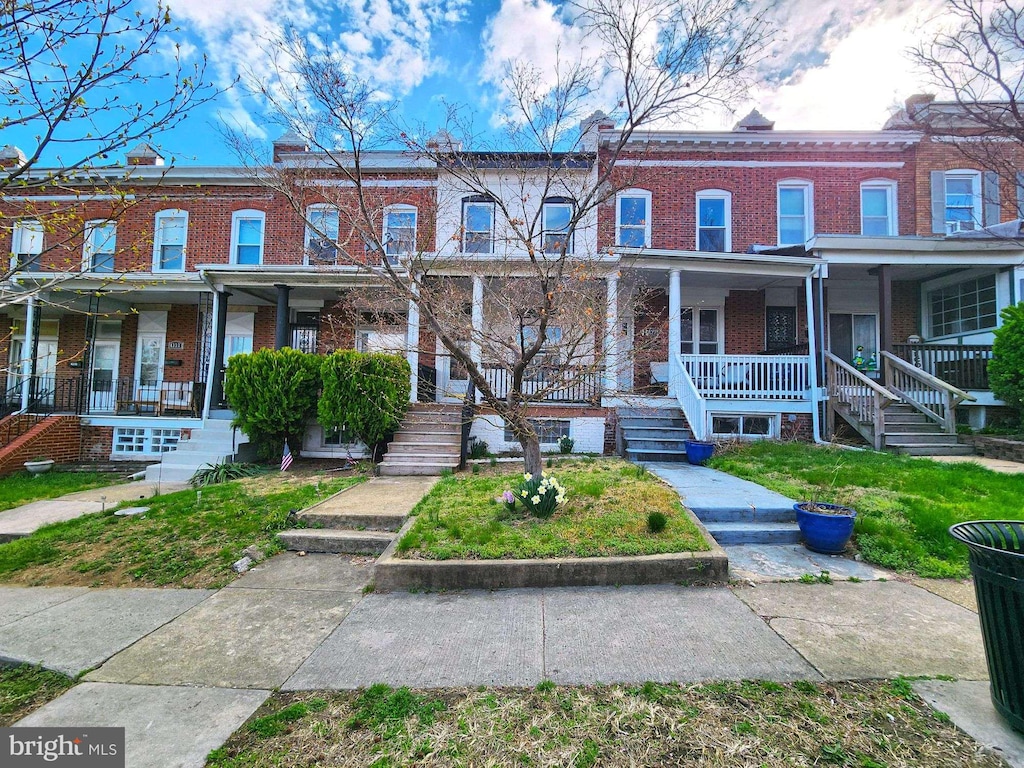 townhome / multi-family property featuring stairs, a porch, and brick siding