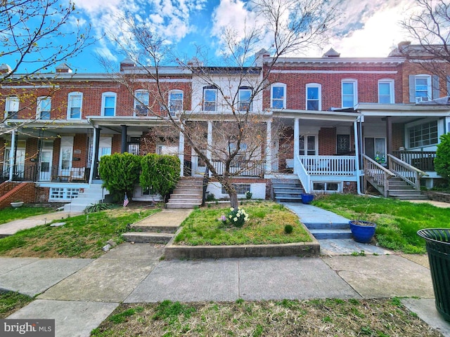townhome / multi-family property featuring stairs, a porch, and brick siding