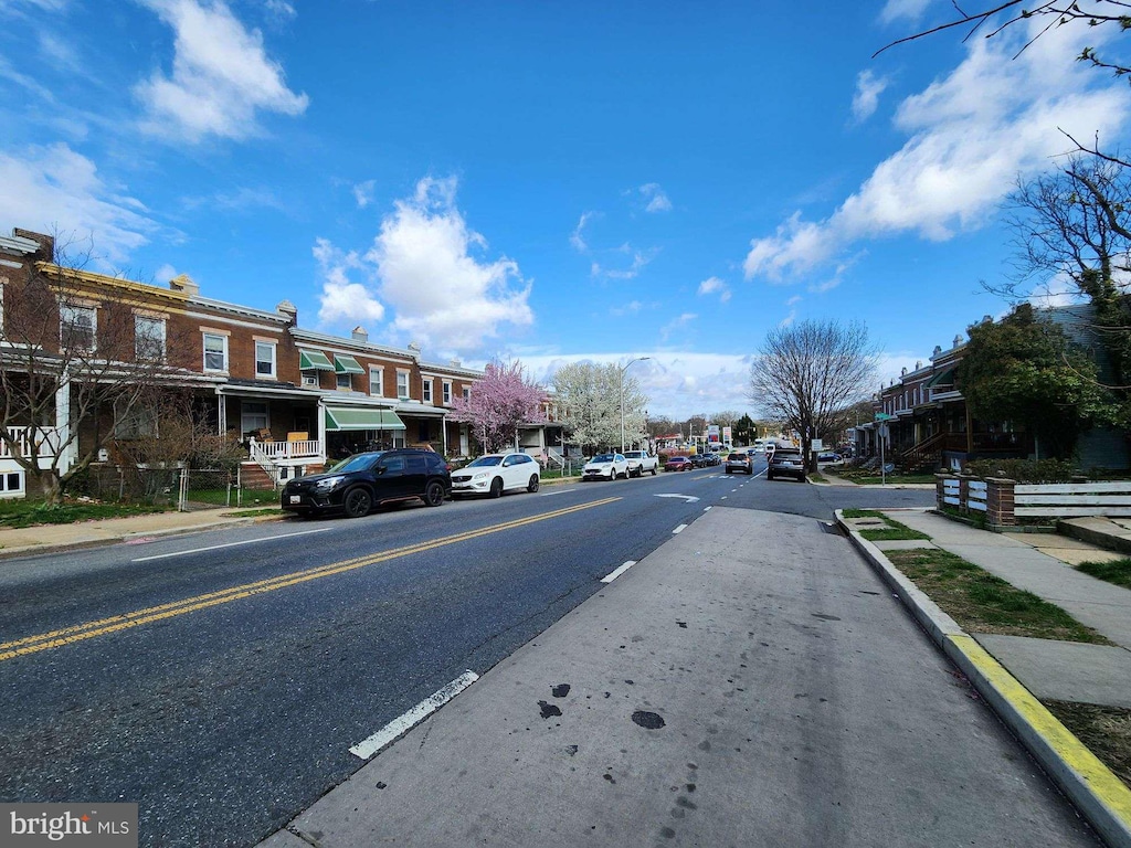 view of street with curbs, street lights, sidewalks, and a residential view